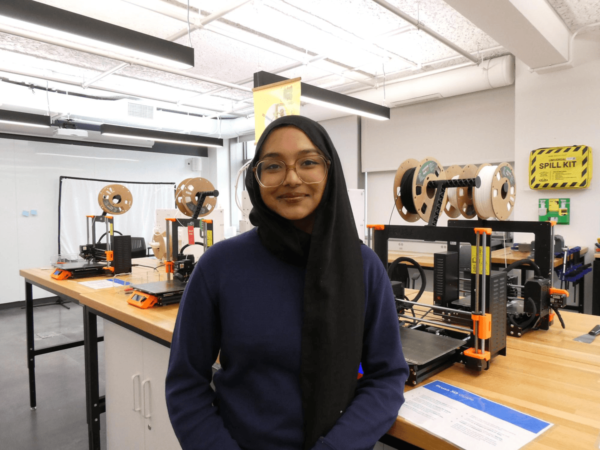 Sabria in front of 3d printers in the design lab